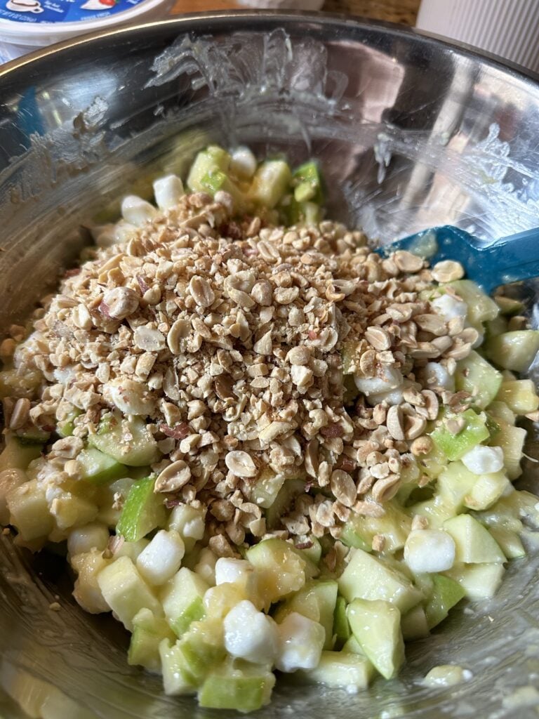Crushed peanuts on top of the Taffy Apple Salad in a metal bowl