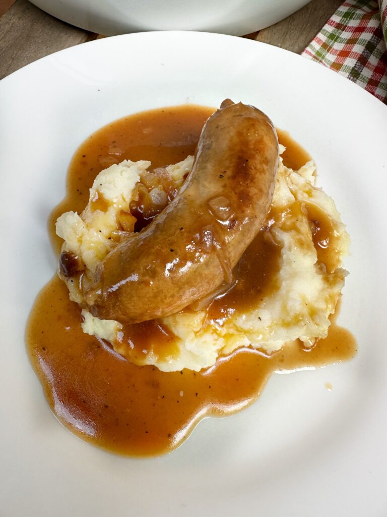 A sausage on mashed potatoes covered in onion gravy