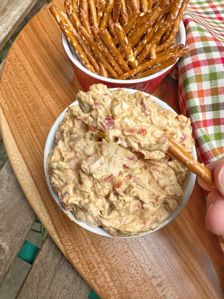 A pretzel stick being dipped into Bourbon Bbq Cheese Pretzel Dip