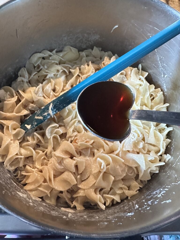 Noodles being stirred in a metal bowl
