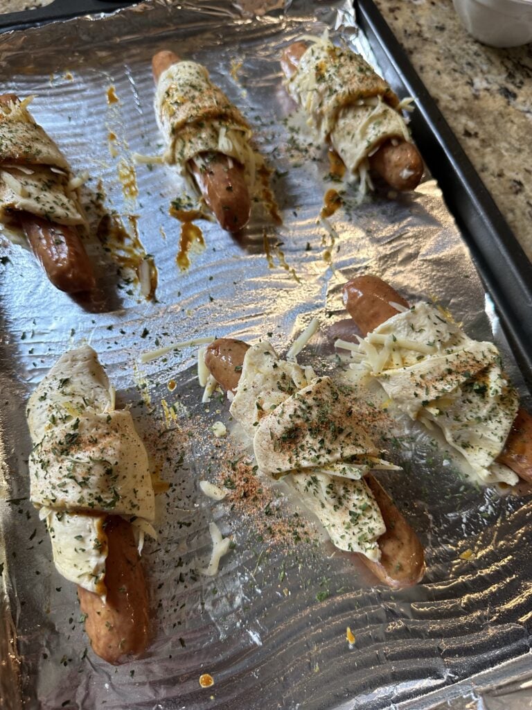 Franks with crescent roll dough wrapped around them before baking