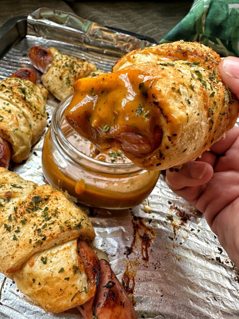 A close up of a frank and Swiss bite that has been dipped in sauce