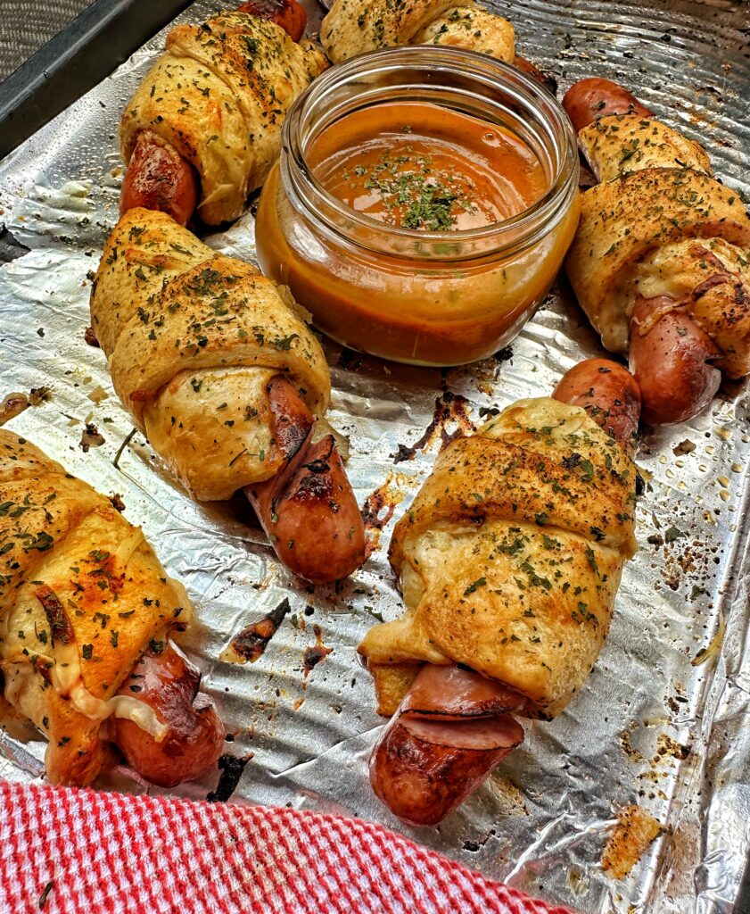 Frank and Swiss bites arranged around a glass container of golden BBQ sauce