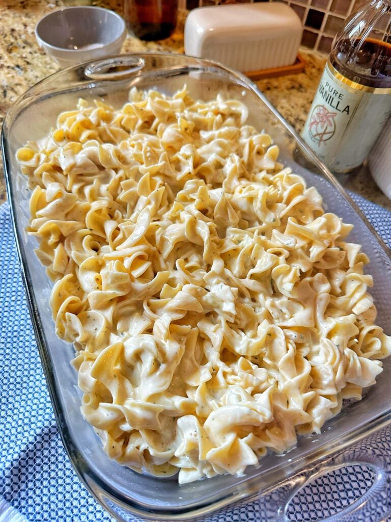 Noodles topped with a soupy mixture in a glass baking dish before being put in the oven