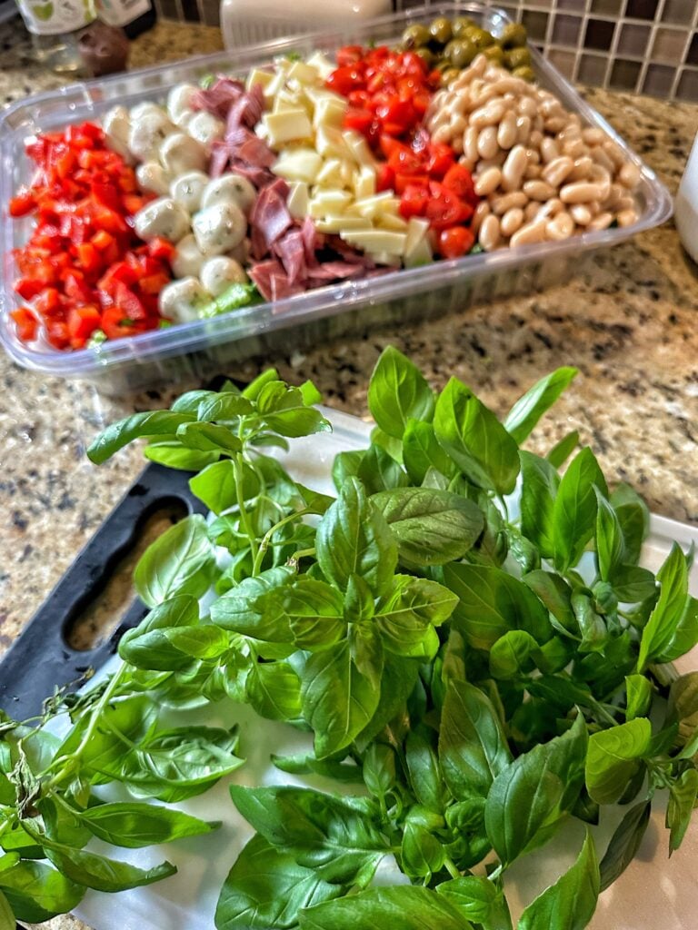 Basil on a white cutting board in front of the Italian Salad