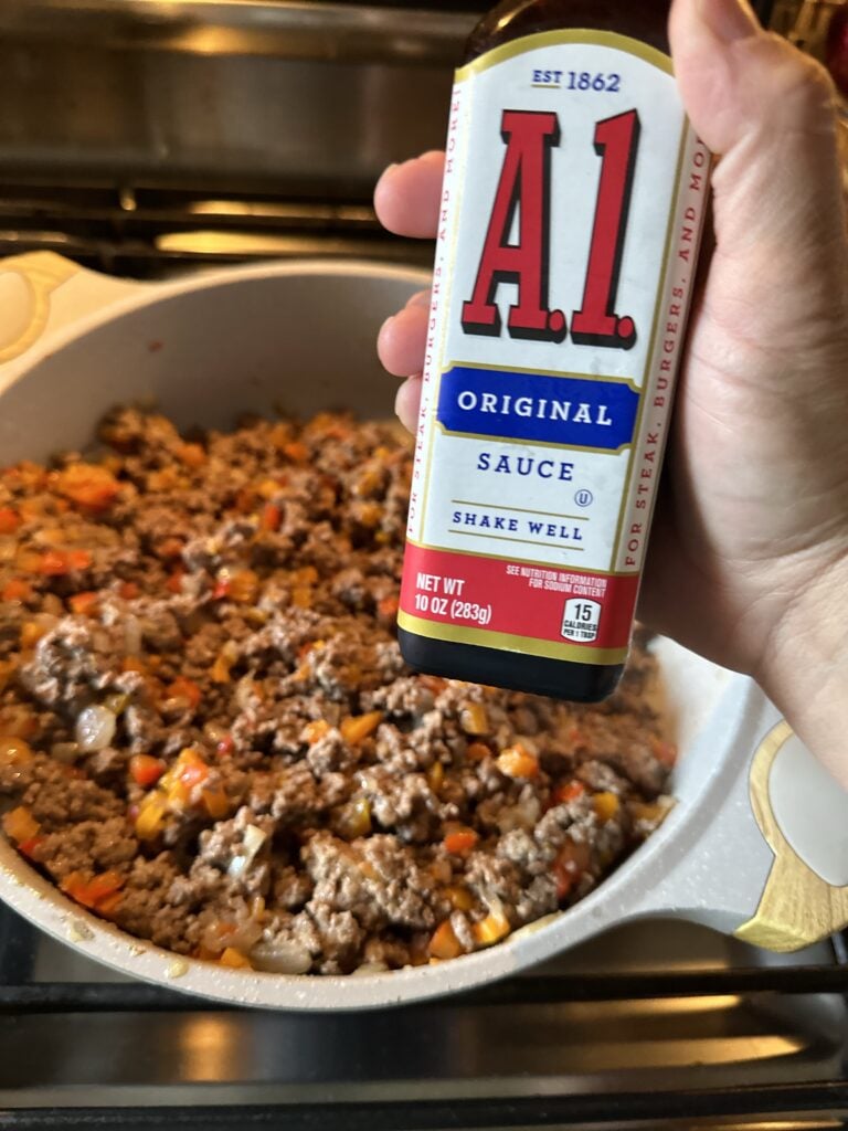 A1 steak sauce held over a pot of ground beef and peppers