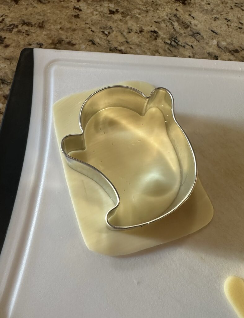 A slice of cheese with a ghost-shaped cookie cutter over it