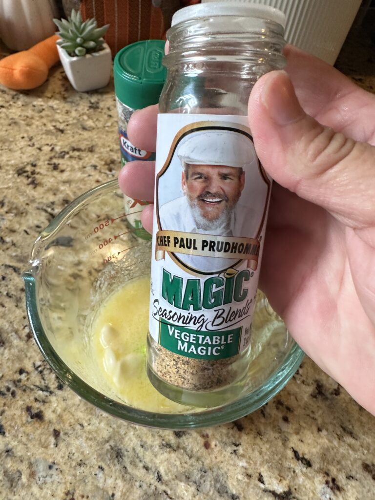 Paul Prudhomme's Magic Seasonig Blend held above a bowl of melted butter