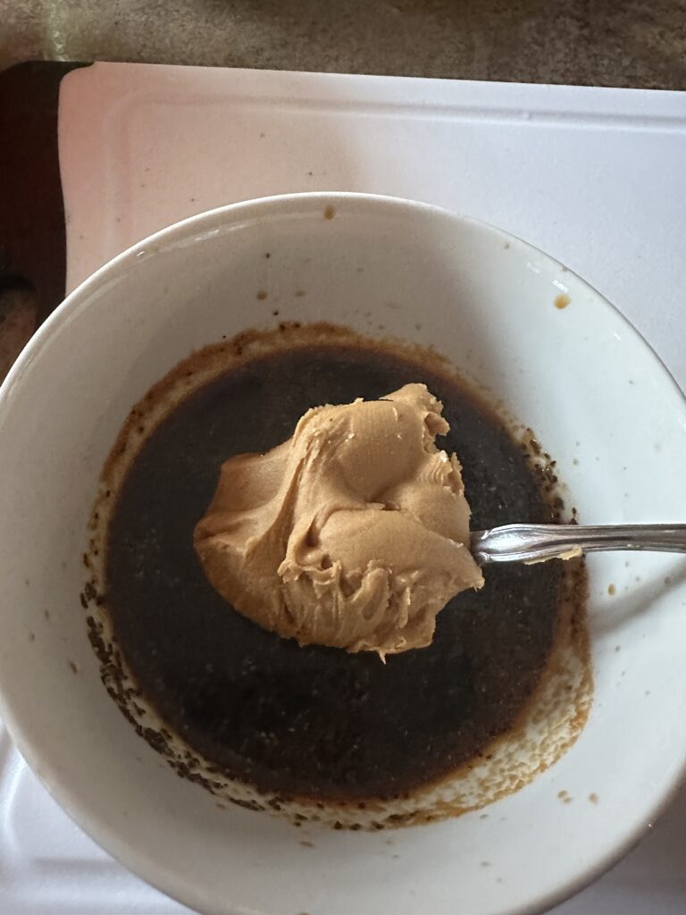A spoon of peanut butter over a soy sauce mixture