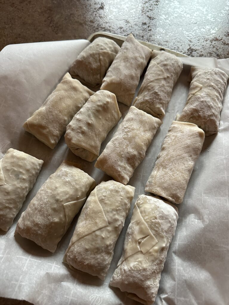 The wrapped but raw egg rolls on a tray
