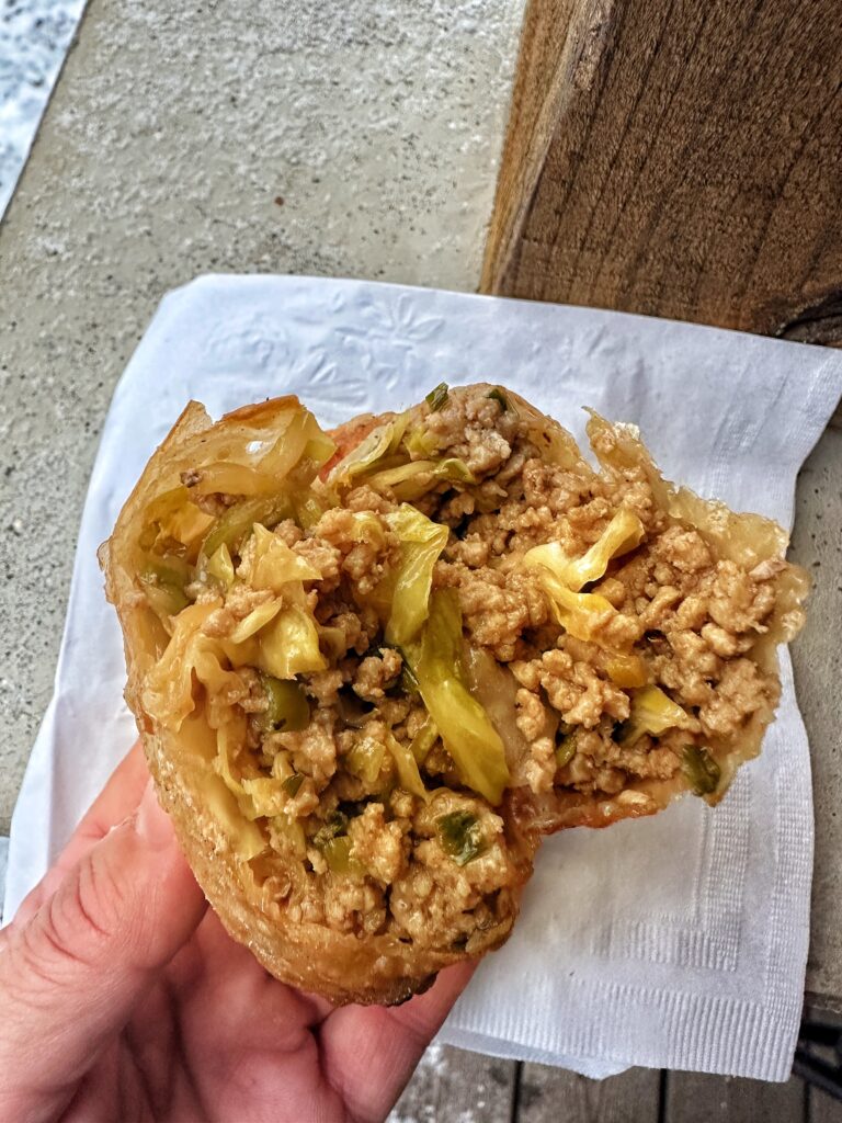 An egg roll with a bite taken out so the inside can be seen