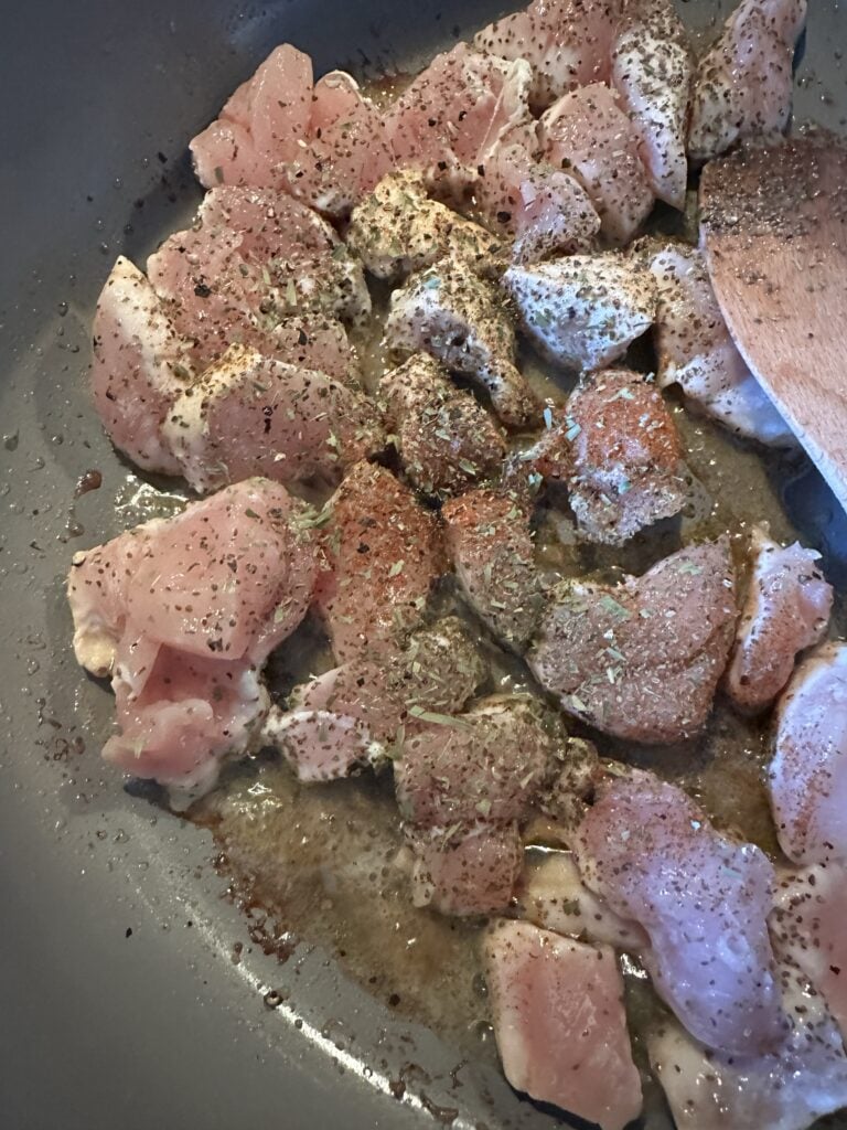 Chicken covered in spices cooking in a skillet