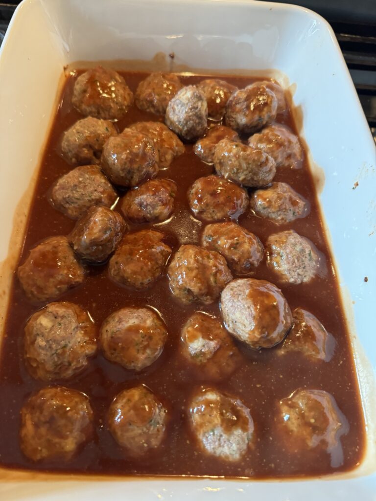 Raw ham balls in a baking dish in sauce