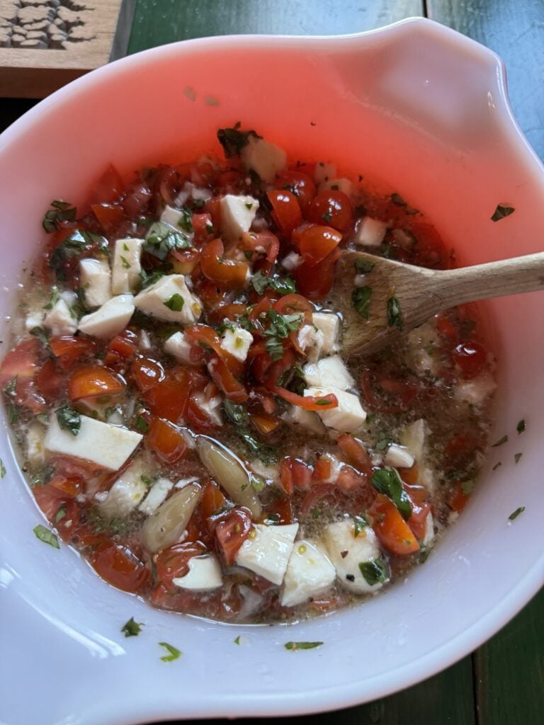 Garlic, tomato, mozzarella, and basil in a bowl