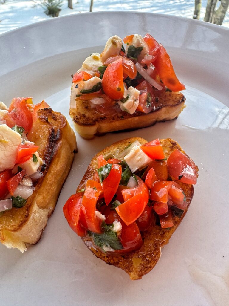 Three finished bruschetta toasts on a plate