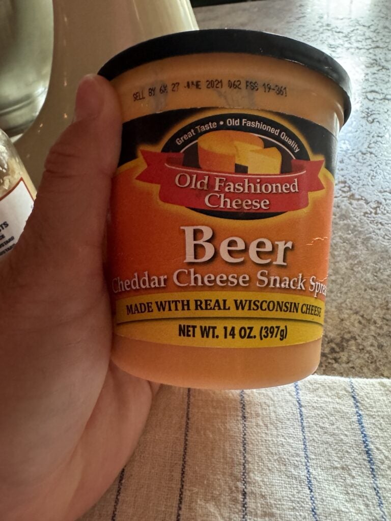 A container of Old Fashioned Beer Cheese spread being held by me