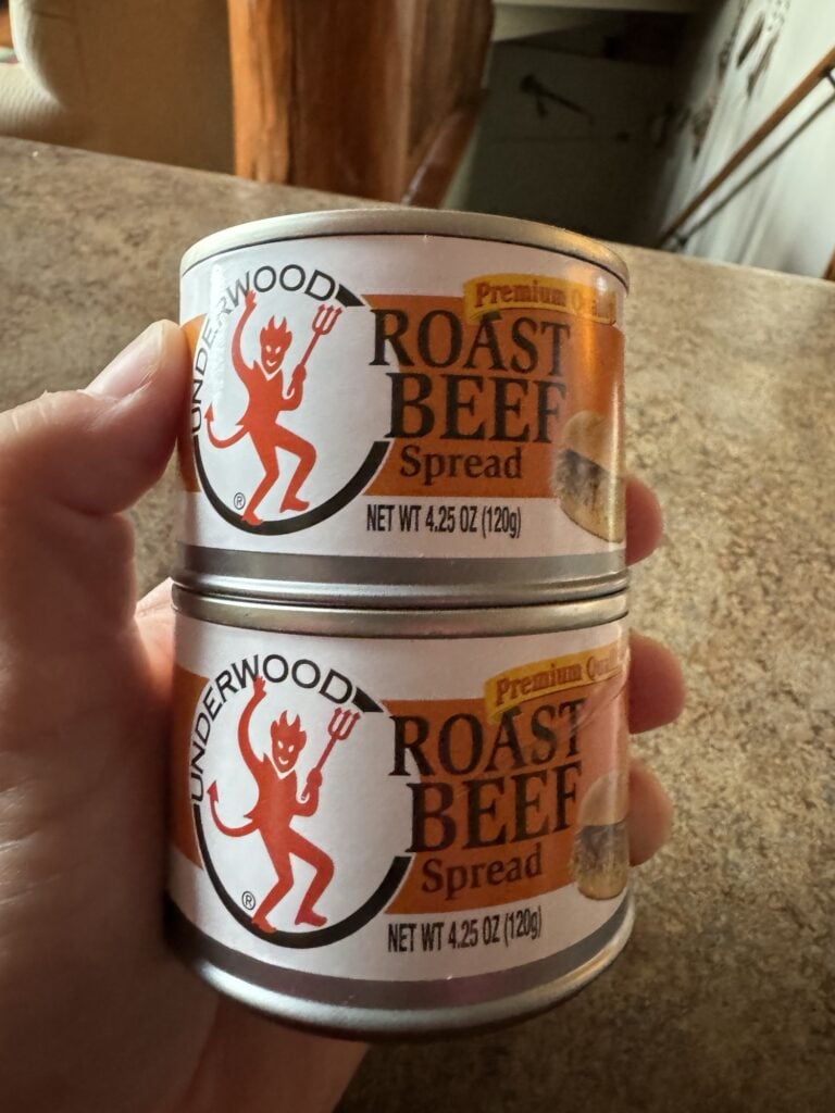 Two cans of Underwood Roast Beef spread, stacked and held in my hand