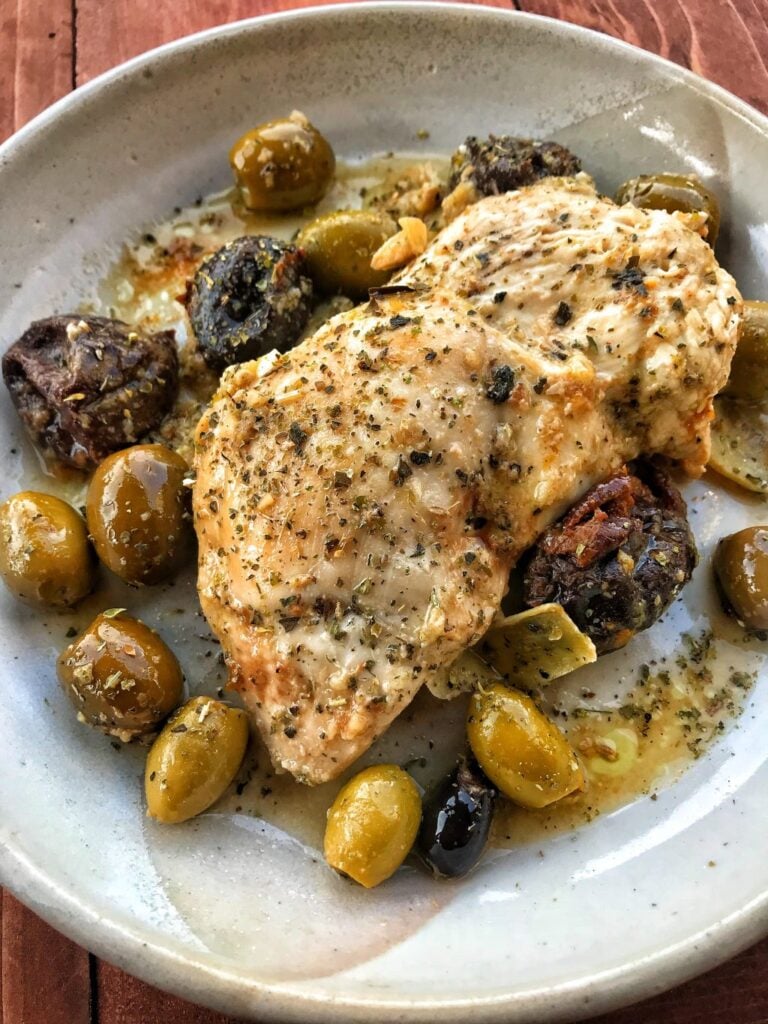 Chicken breast on a late with olives and savor plums in a herbed oil