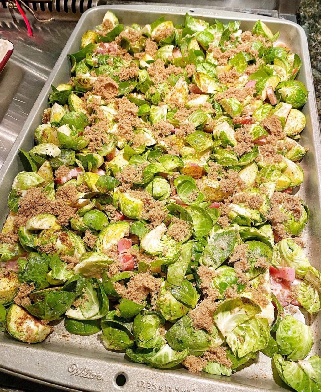 A sheet pan with Brussels Sprouts, with a sprinkle of bacon , brown suagr, about to go into the oven