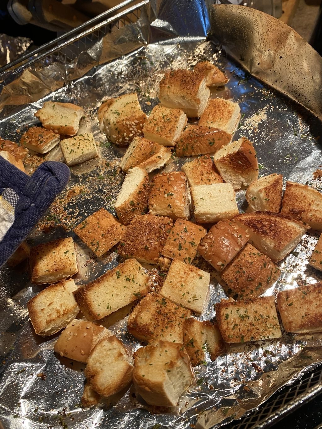 Cubed, toasted hamburger bun pieces on a foil baking sheet