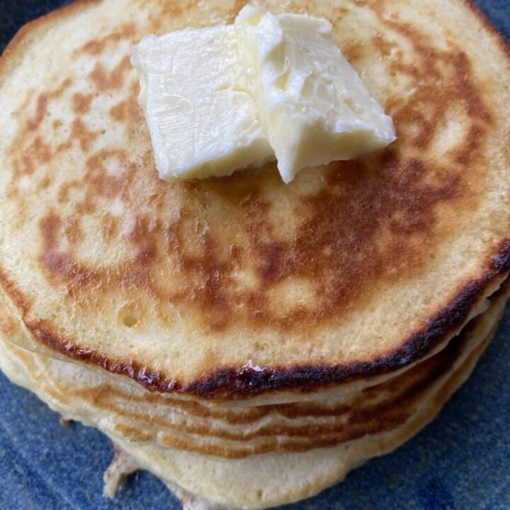 Plate of pancakes with a butter all sitting on top of a blue plate