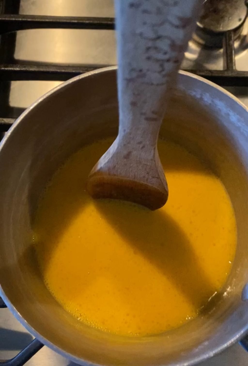 Cracked eggs in a pot with a wooden spoon