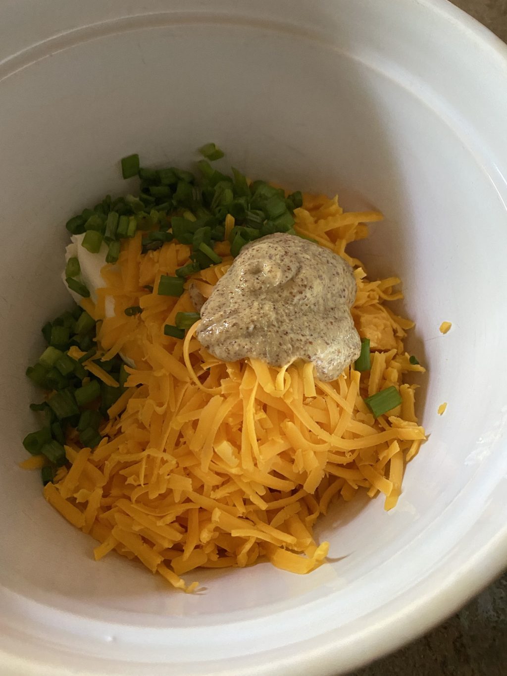 Chopped green onions, shredded cheddar cheese, and sauce in a bowl