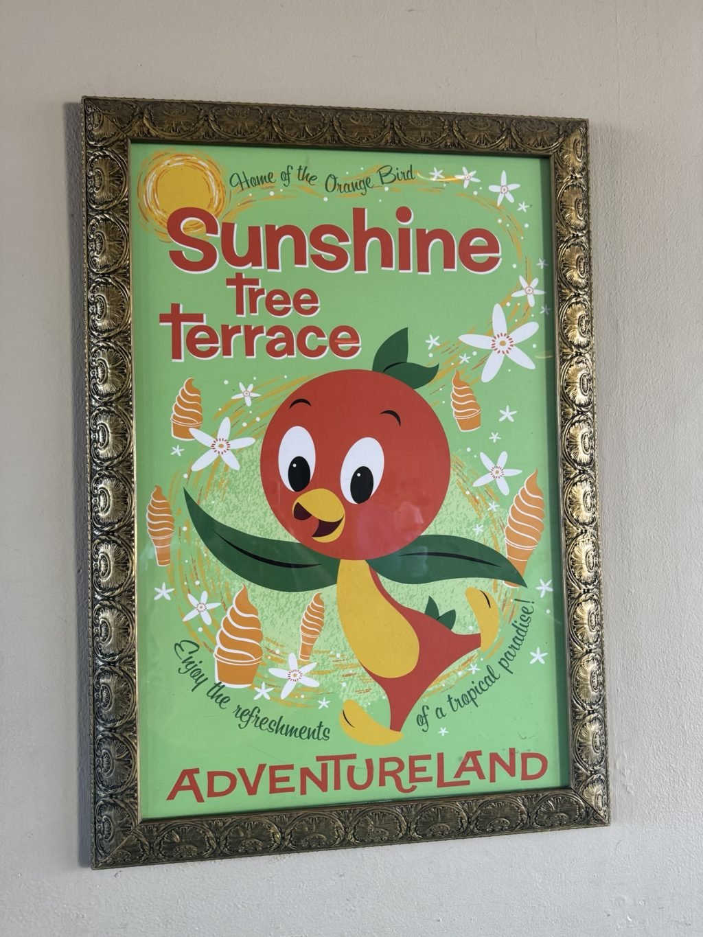 A poster for Sunshine Terrace in Adventureland with a cartoon bird surrounded by orange ice cream swirls