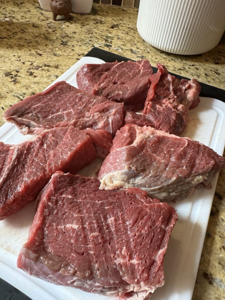 Tenderized chunks of beef on a white cutting board
