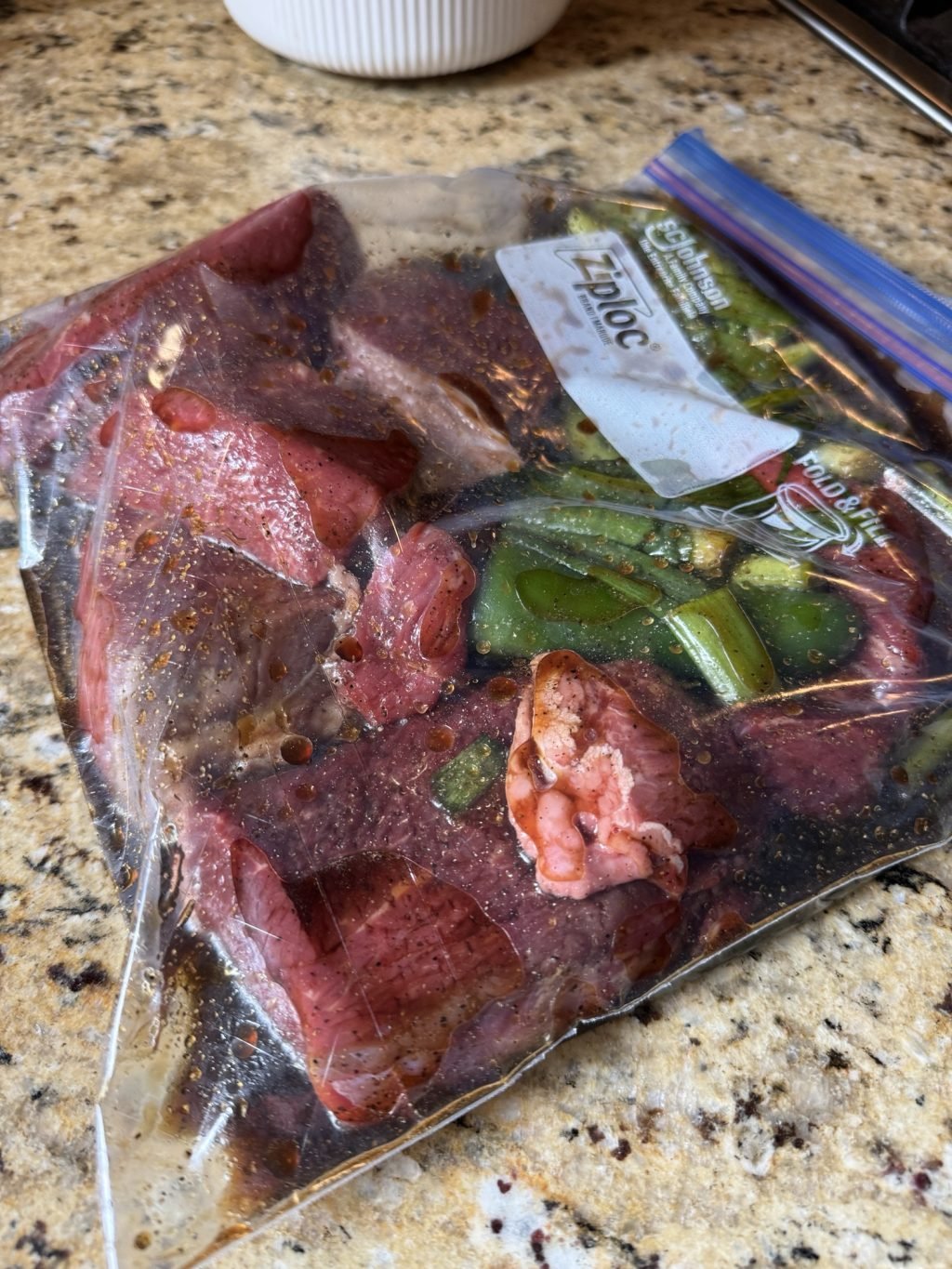 The raw beef, onions, jalapeno, and marinade mixing together in a plastic Ziploc bag
