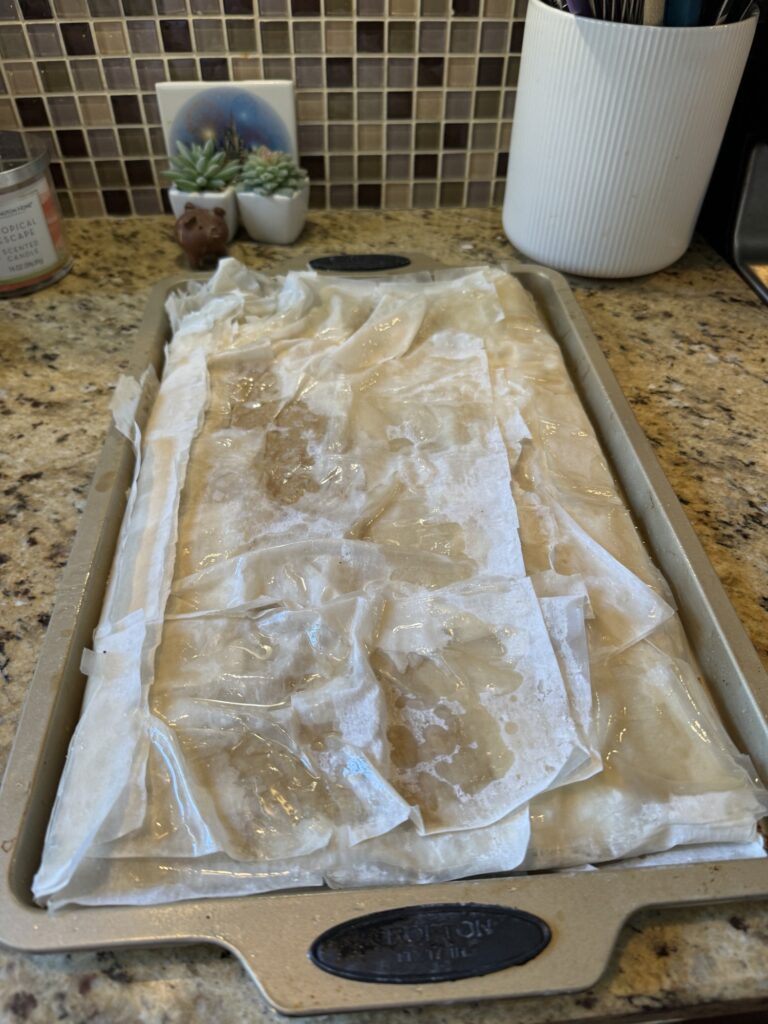 The Phyllo dough folded over the meat mixture in a baking dish on the kitchen counter