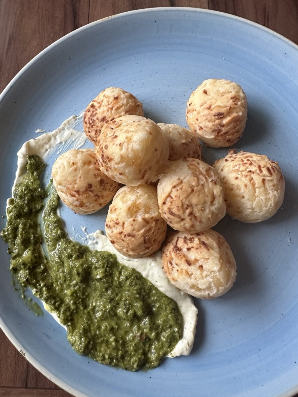 Dough balls with a green and white sauce on a blue plate