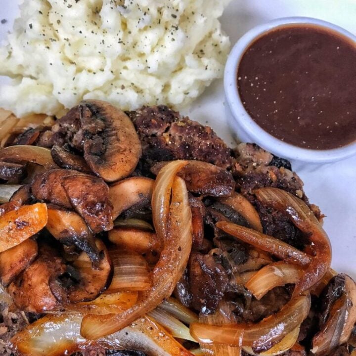 Chopped steak with onions and mashed potatoes and steak sauce.