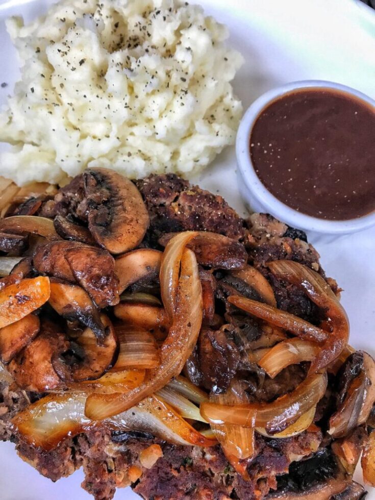 Chopped steak with onions and mashed potatoes and steak sauce.