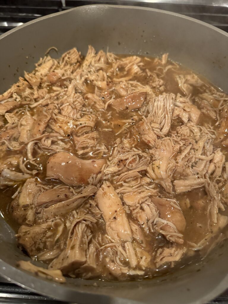 Shredded chicken in gravy in a pan.