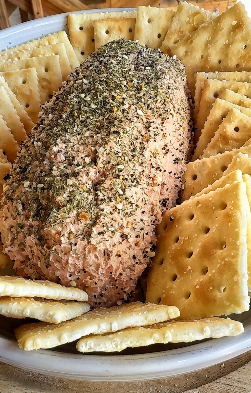 A close up of a loaf of liver sausage spread surrounded by Saltine crackers.