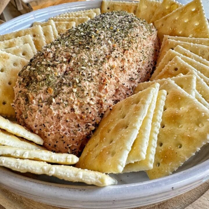 A loaf of liver sausage spread surrounded by Saltine crackers.