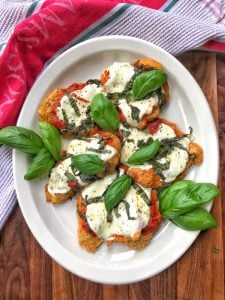 Chicken cutlets topped with cheese, tomato sauce, and basil.