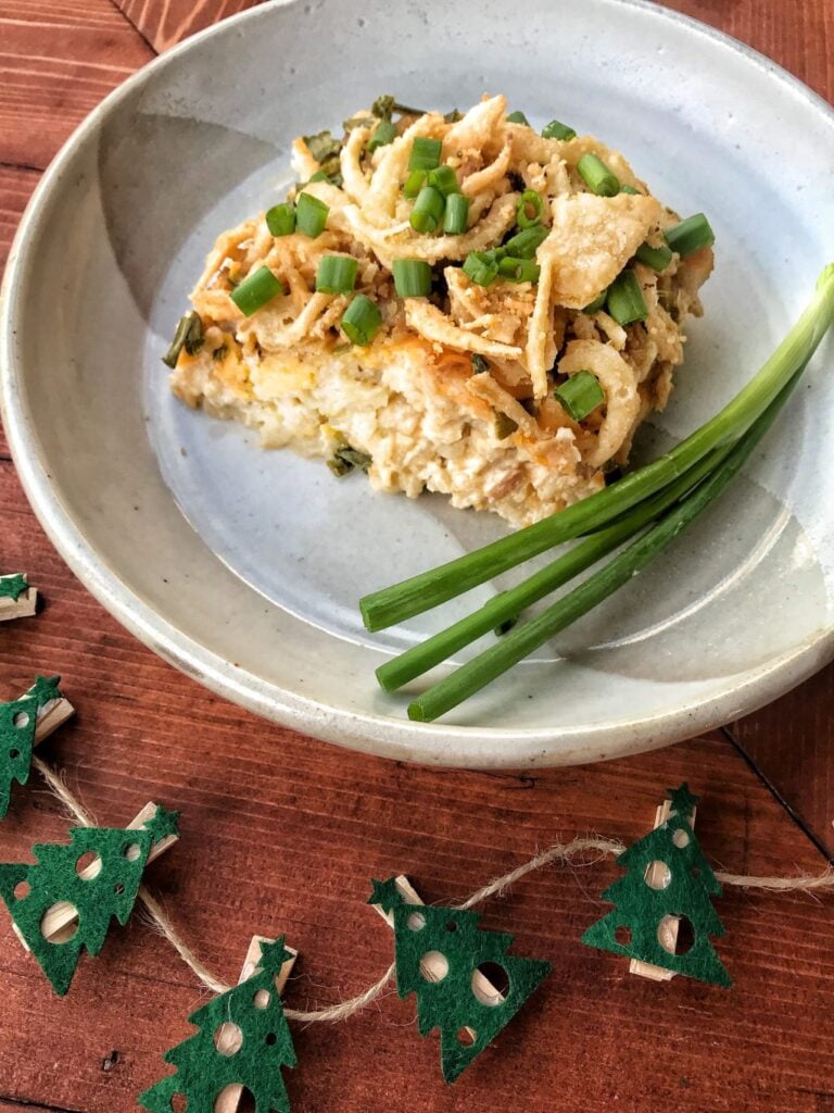 A slice of crockpot potatoes on a plate with green onions.