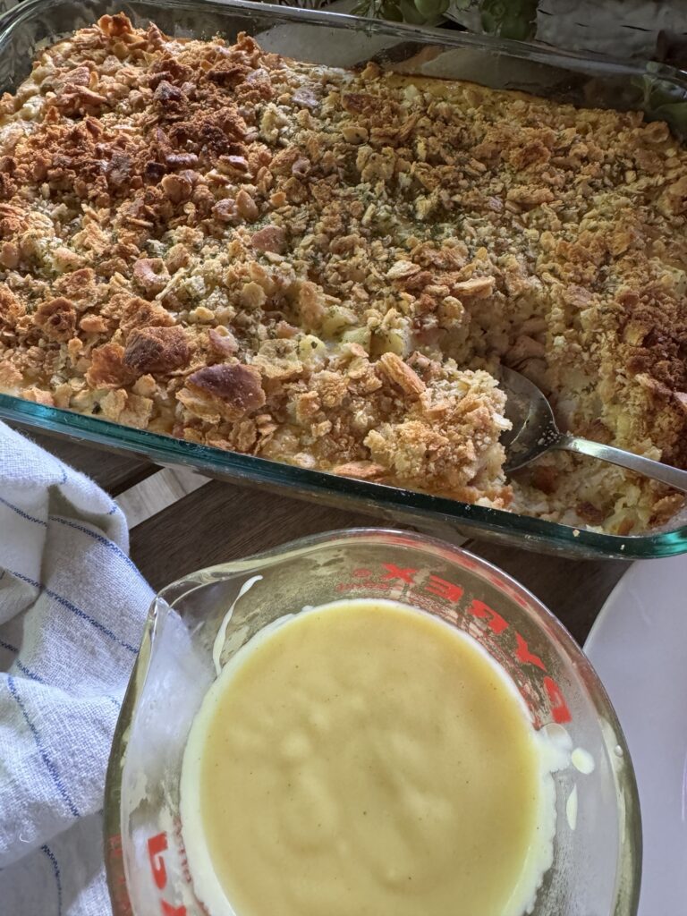 The casserole next to a measuring cup of the sauce.