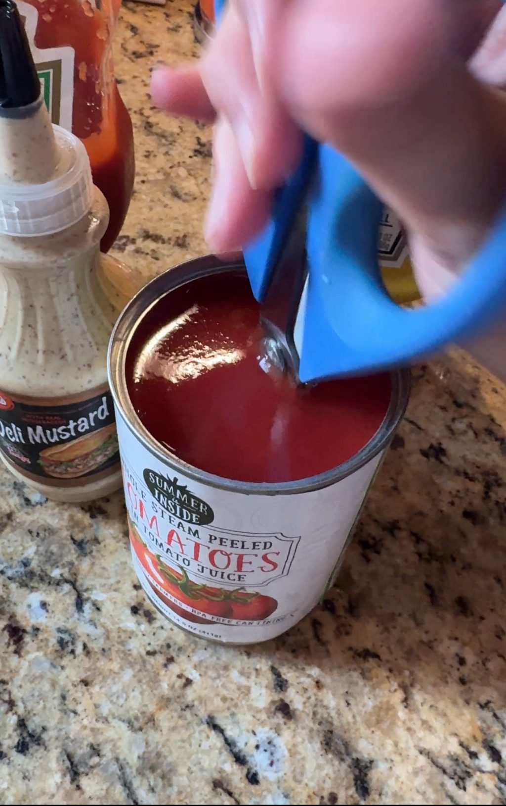 A pair of kitchen shears inserted into a can of tomatoes in tomato juice.