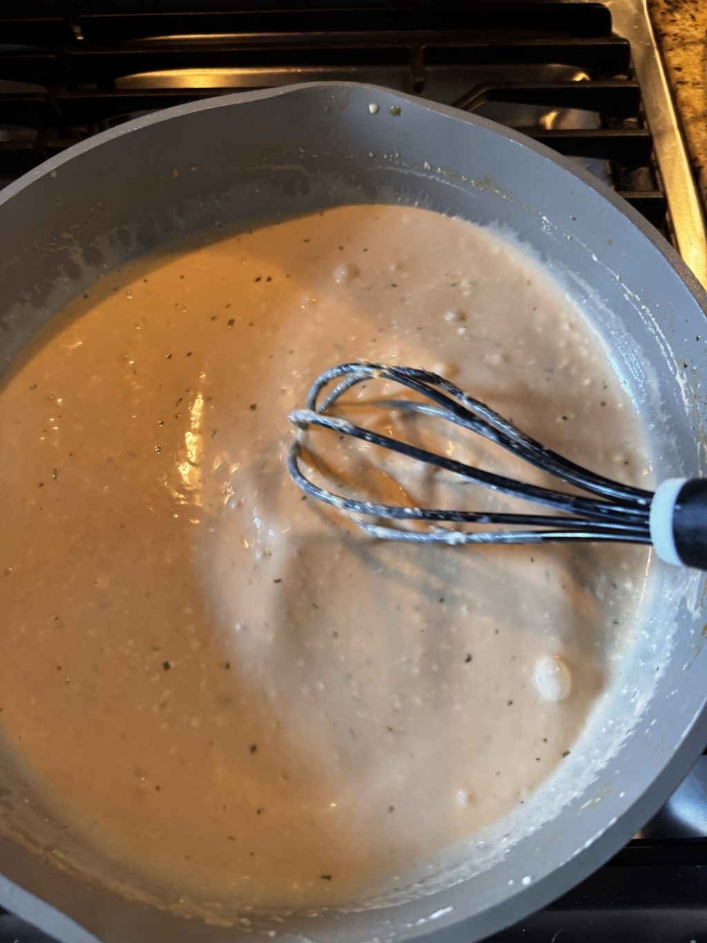 The lobster pasta sauce in a pot with a whisk.