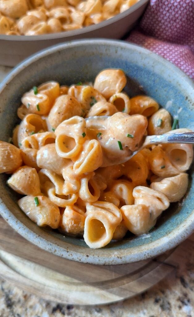 A bowl of poor man's lobster pasta with a spoon of the pasta held over it.