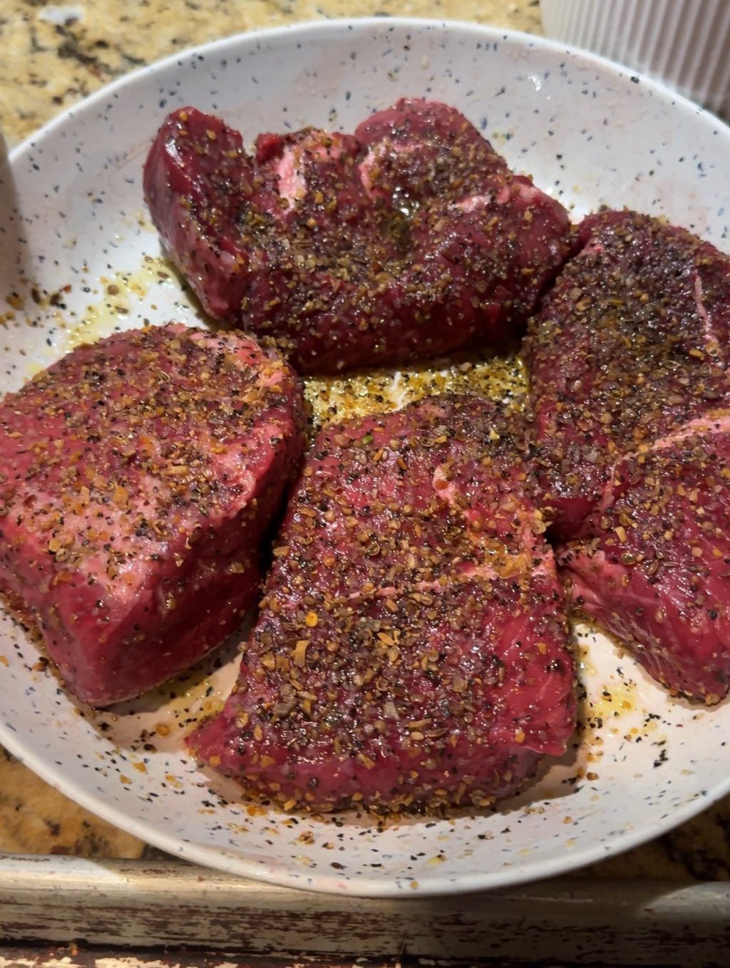 Four raw, seasoned sirloin filets.