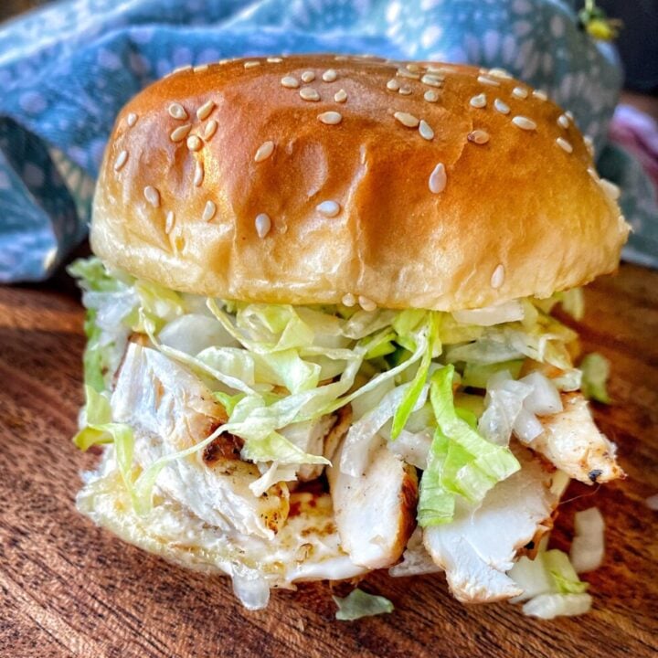 A grilled chicken sandwich with shredded lettuce on a sesame seed bun.