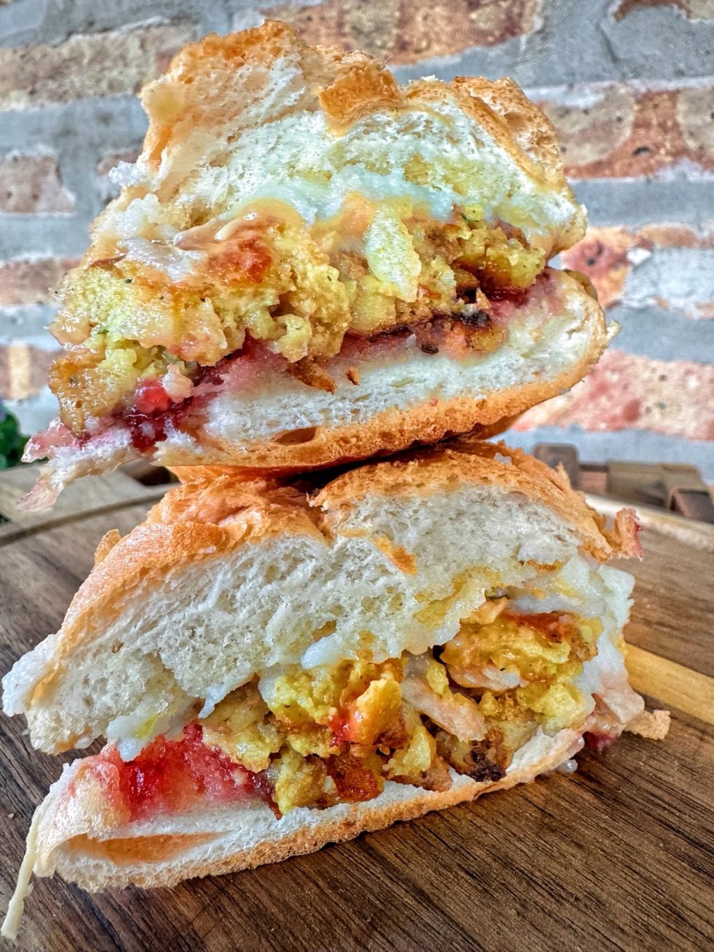 A Thanksgiving leftover sandwich cut in half with the two halves stacked on top of each other.