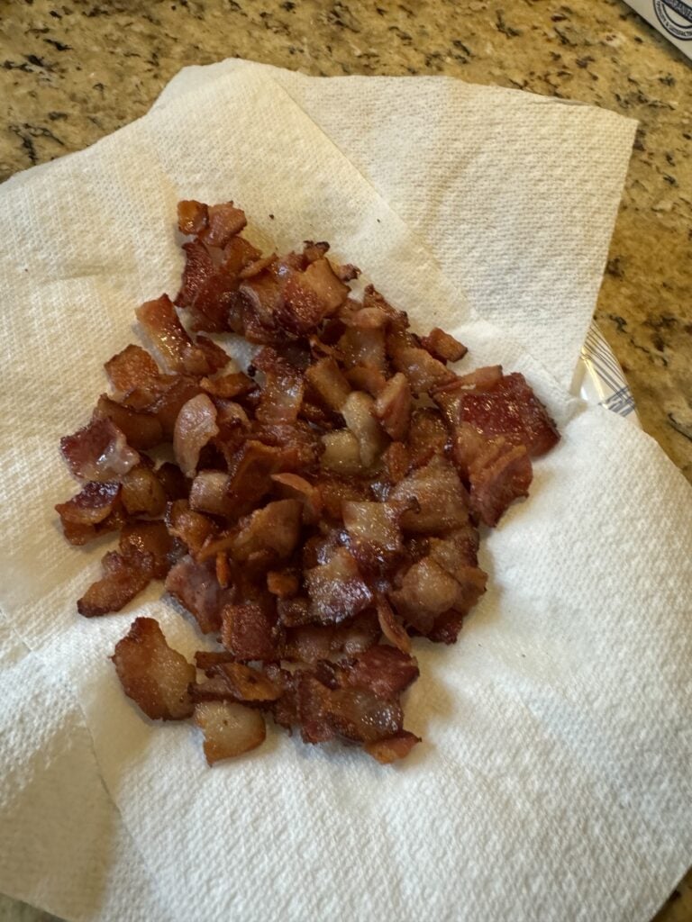 Cooked, diced bacon on a paper towel.