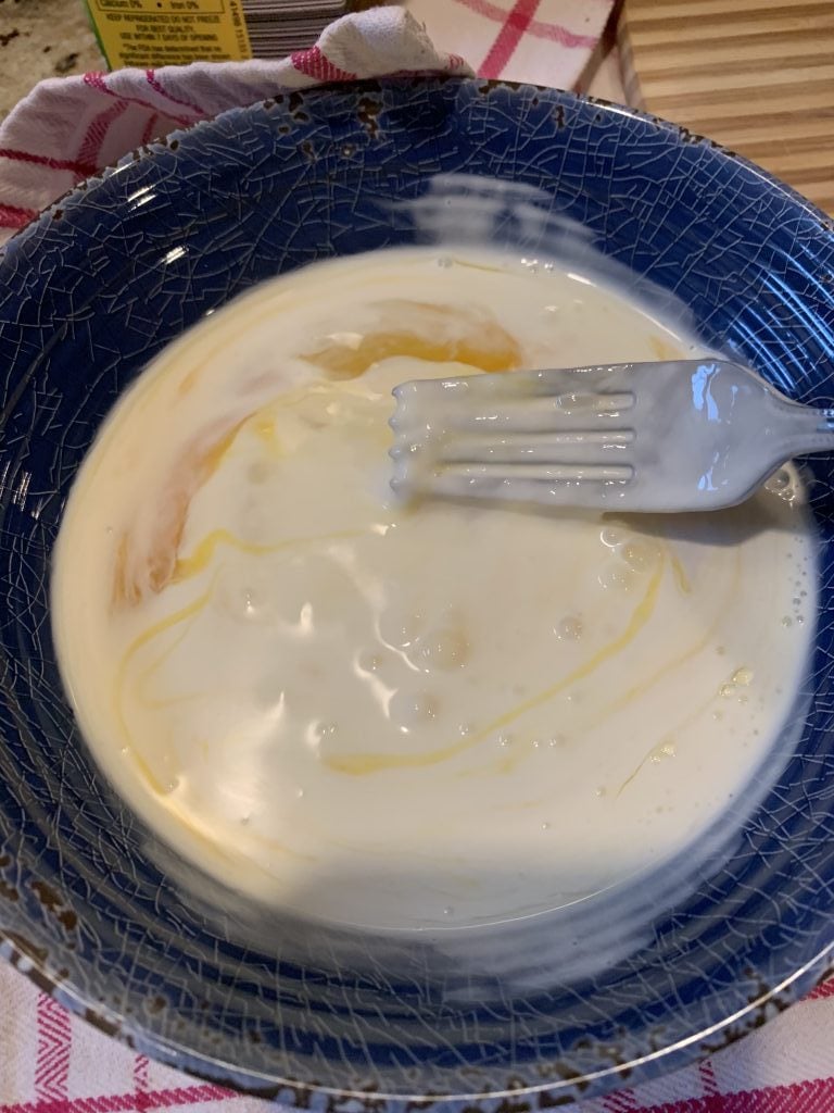Sauce being mixed in a bowl with a fork.