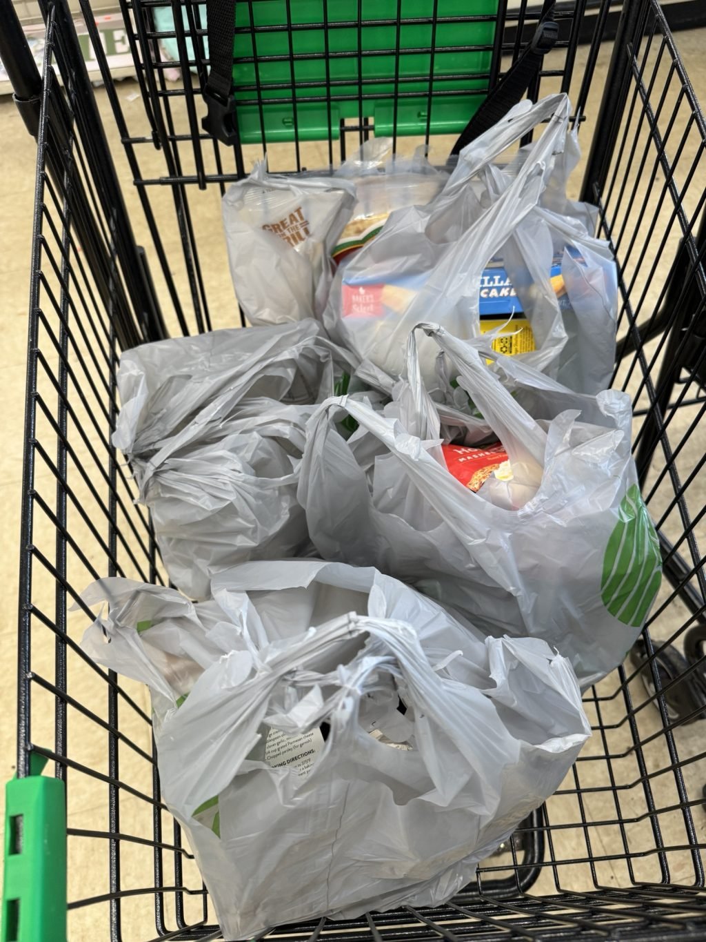 A shopping cart full of groceries in gray plastic bags.