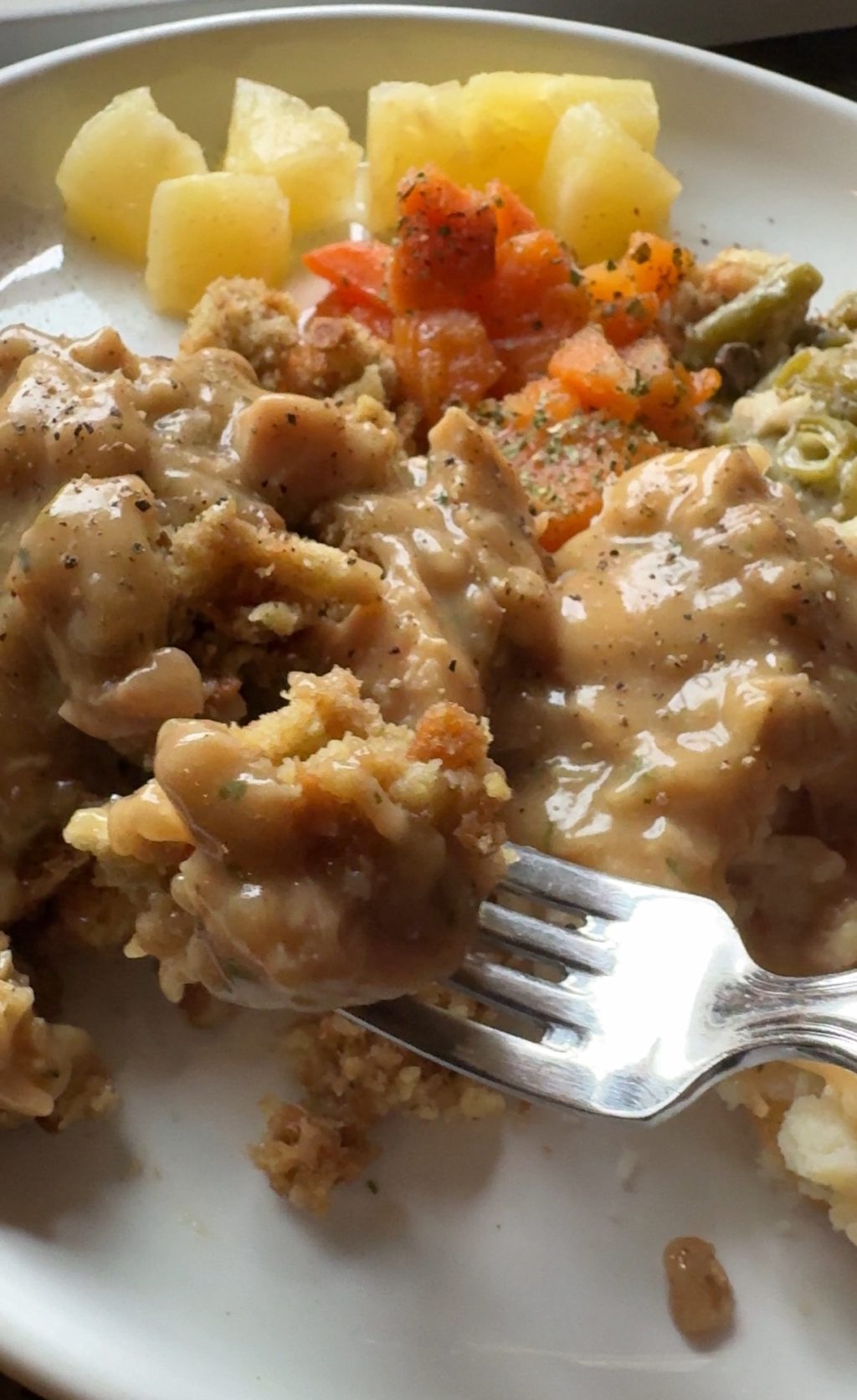 A fork with a chunk of stuffing covered in gravy.